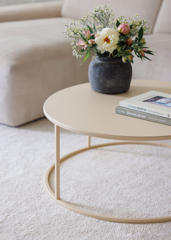 Beige rundt sofabord versina fra metallbude